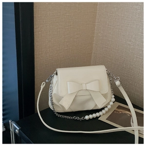 Detailed close-up of cream-white bag featuring 3D bow design and elegant pearl chain strap