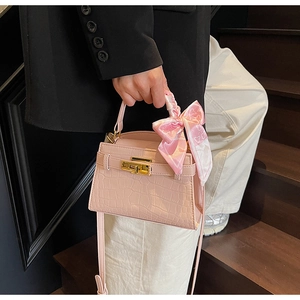 Détail du sac à main rose gaufré croco avec fermoir doré et foulard en soie décoratif