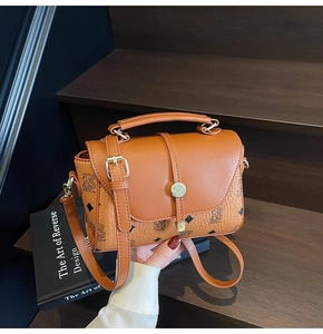 Detailed close-up of brown textured crossbody bag with bear print and golden lock on wood