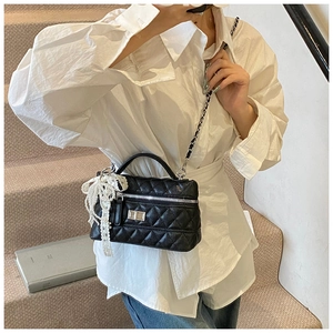 Detail of black quilted chain bag with silver twist lock and pearl lace pendant charm