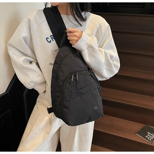 Détail d'un sac de poitrine en nylon noir avec compartiments porté par un mannequin