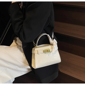 Détail du sac à main crème texture crocodile avec foulard en soie et fermoir doré