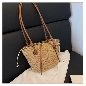Detail of straw woven tote with brown leather strap and white drawstring closure