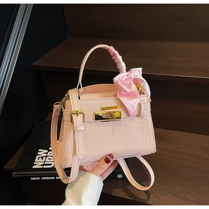 Gros plan du sac à main rose gaufré croco avec fermoir doré et détail de foulard en soie
