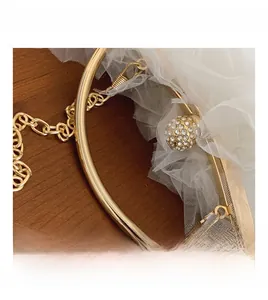 Close-up of golden metal handle and diamond-encrusted clasp on a lace evening bag