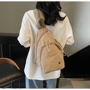 Gros plan d'un sac à bandoulière kaki avec fermetures éclair et sangle tissée sur un mannequin