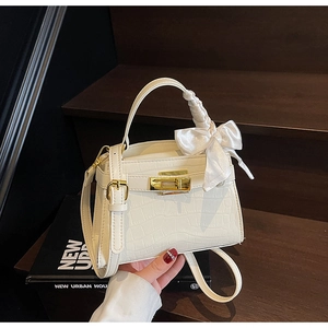 Détail du sac à main crème effet crocodile avec fermoir doré et décoration en nœud satiné