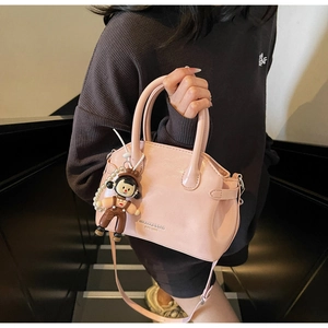 Dettagli della borsa rosa in pelle cerata con ciondolo a bambola rimovibile e tracolla