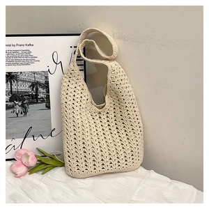 Detail of cream woven tote bag featuring hollow crochet pattern on a textured white surface