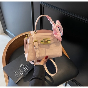 Détails du sac à main rose gaufré crocodile avec fermoir doré et ruban en soie