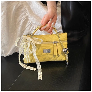 Close-up of yellow quilted leather crossbody bag with lace bow and pearl chain detail