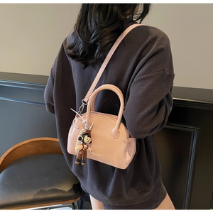 Dettaglio borsa in pelle cerata rosa chiaro con ciondolo a cartone e tracolla sottile
