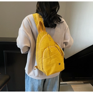 Détail du sac de poitrine en nylon jaune avec plusieurs poches zippées et logo rond