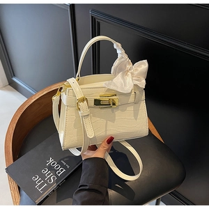 Détail du sac à main blanc motif crocodile avec nœud en soie et fermoir doré chic
