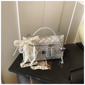 Detailed shot of silver quilted mini bag featuring a large lace and pearl bow accent