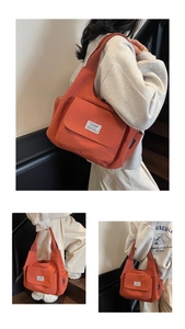 Detail view of large orange canvas shoulder bag with front pocket and CHUANGMI logo label