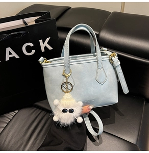 Close-up of light blue leather bucket bag featuring fashion embossing and furry charm