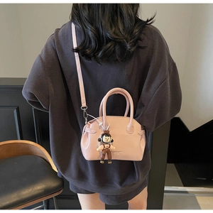 Dettaglio della borsa rosa in pelle cerata con ciondolo a cartone e tracolla