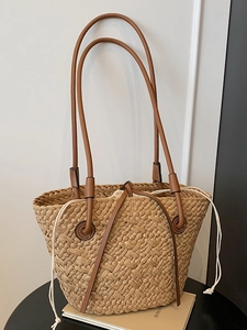 Minimalist straw tote bag with brown leather handles and drawstring lining for summer beach
