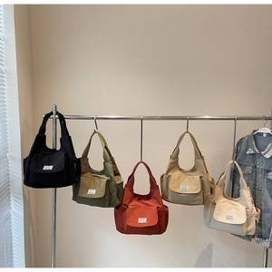 Multi-color minimalist tote bags collection hanging on rack with front pocket detail