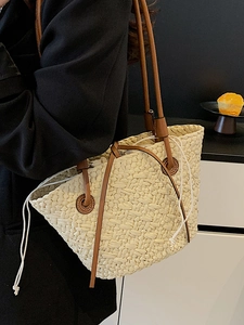 Minimalist straw shoulder tote bag with brown leather straps shown on a model