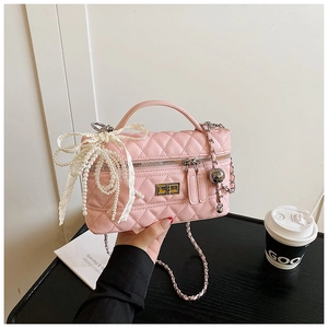 Detail of pink quilted crossbody bag with pearl lace bow and golden chain strap