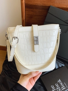 Elegant white bucket bag with stone texture, silver buckle, and slim leather shoulder strap