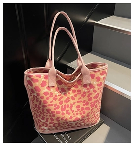 Close-up of pink leopard print canvas tote bag with durable woven handles on books