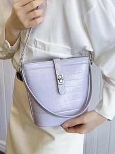 Chic lilac bucket bag with crocodile texture and silver twist lock on a white shirt model