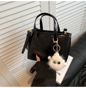 Detail of black faux leather bucket bag with cute plush monster charm and top handles