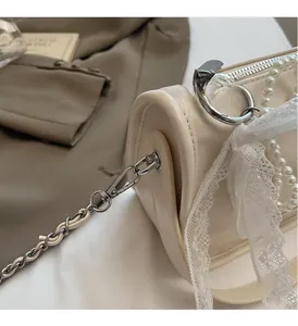 Detail of soft cream leather pillow bag featuring elegant lace trim and pearl accents