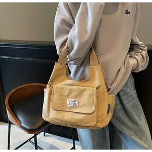 Detail view of khaki canvas tote bag featuring large front flap pocket and sturdy shoulder strap