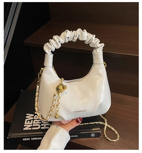 Détail de la poignée plissée et de la bandoulière en chaîne dorée sur le sac hobo blanc