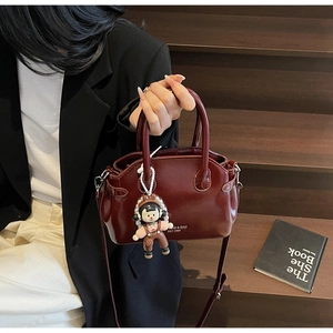 Borsa a mano vintage in pelle bordeaux tenuta da una modella su una scala