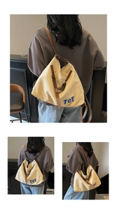 Detail of canvas tote bag with brown leather straps and blue TCT letter embroidery