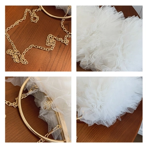Detail of white tiered lace mesh handbag with golden chain strap and sparkling crystal clasp