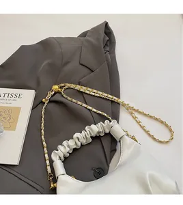 Détail du sac à main blanc avec poignée plissée et chaîne dorée sur fond de blazer