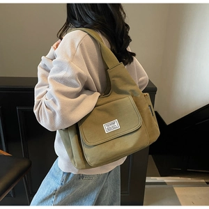 Detail of army green canvas shoulder bag showing the large capacity and side utility pocket