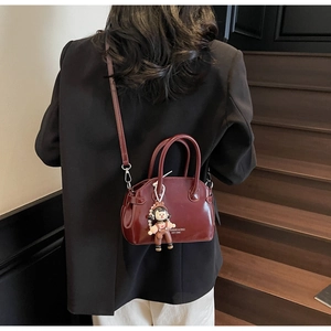 Borsa a mano retrò bordeaux in pelle cerata indossata a spalla in un contesto di stile