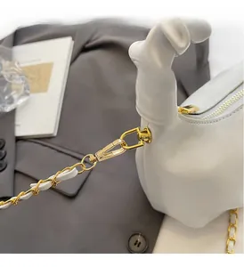 Détail du sac en cuir blanc plissé avec chaîne dorée et mousquetons métalliques