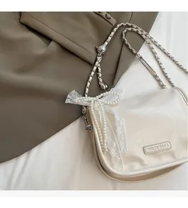 Detail of soft leather handbag with elegant pearl and lace bow decoration on dark background