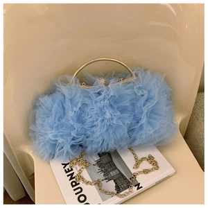 Close-up of light blue mesh bag with layered ruffles, golden handle, and crystal clasp
