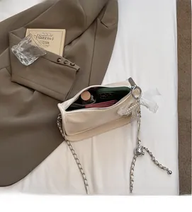 Detail view of cream leather crossbody bag interior with silver chain and pearl charm