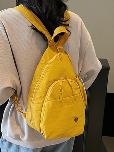 Sac bandoulière en nylon jaune avec plusieurs fermetures éclair porté par un mannequin