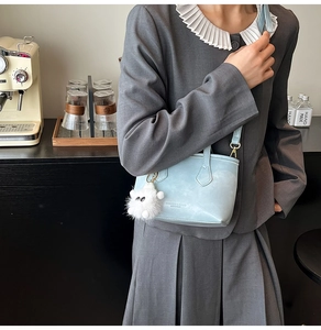 Detail of light blue leather bucket bag with cute white plush monster keychain charm