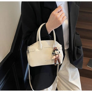 Dettaglio borsa in pelle bianco crema con tracolla regolabile e ciondolo bambola