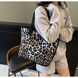 Detailed view of the leopard print tote bag carried by a model in a stylish outfit