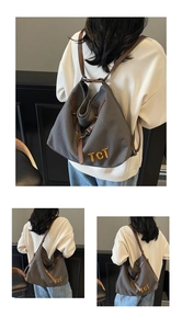 Detail view of dark grey canvas tote with brown leather straps and yellow TCT embroidery