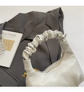 Détail du sac à main blanc plissé avec poignée souple et fermeture éclair dorée