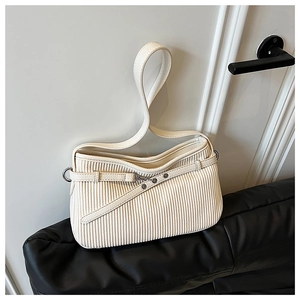 Détail de la texture plissée verticale et de la sangle à rivets d'un sac cabas en cuir beige